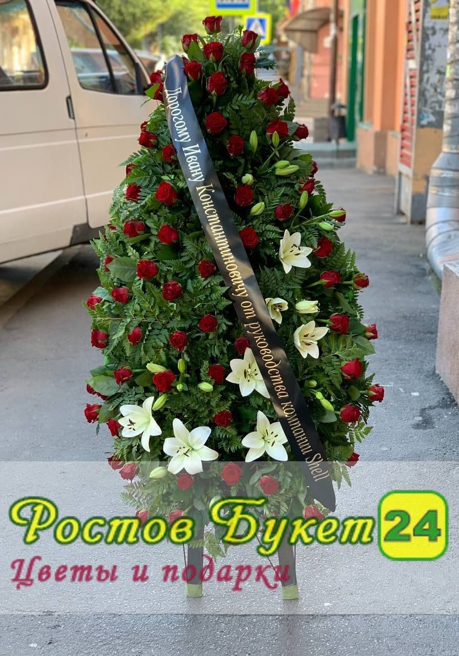 Траурный венок из красных роз и белых лилий.