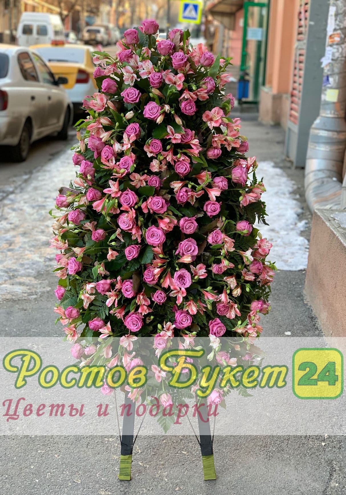 Траурный венок из красных роз и белых лилий.
